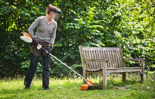 Eine Frau Trimmt ihren Rasen mit einem STIHL Freischneider